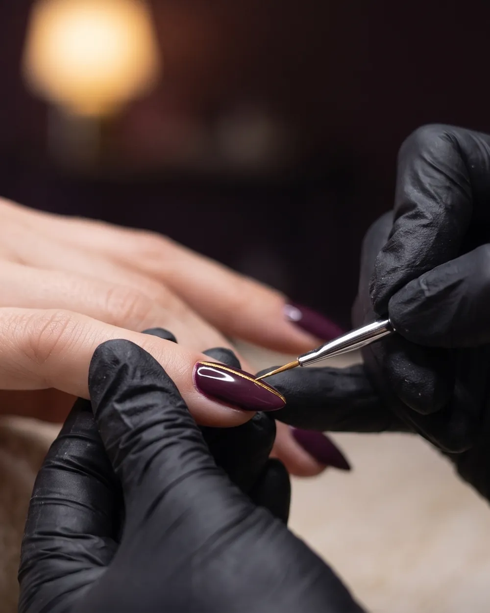 A fine gold line being painted on a long almond nail