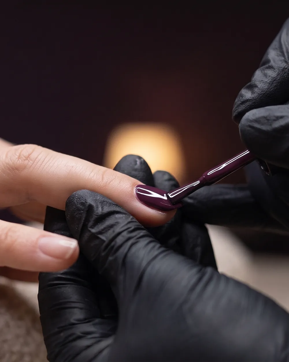 Deep plum gel polish being brushed onto a nail